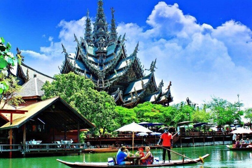 A traditional temple with ornate architecture, a river with boats, and a clear blue sky. 1