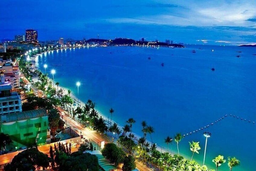 A coastal cityscape at night with illuminated streets, a beach, and a clear sky. 4