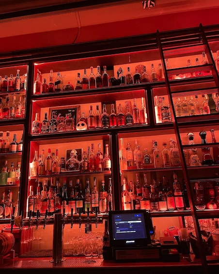 A bar with shelves of liquor bottles and a digital menu display. 5