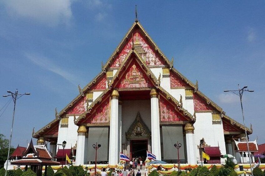 A traditional Thai temple with a red and white facade, golden decorations, and a central entrance. 4