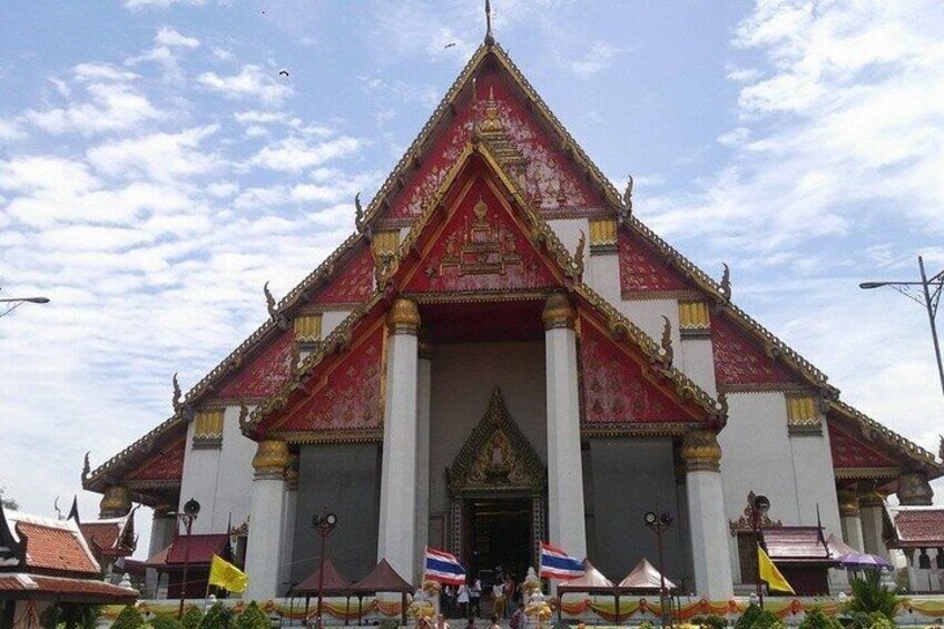 A traditional Thai temple with a red and gold roof, white walls, and a central entrance. 2