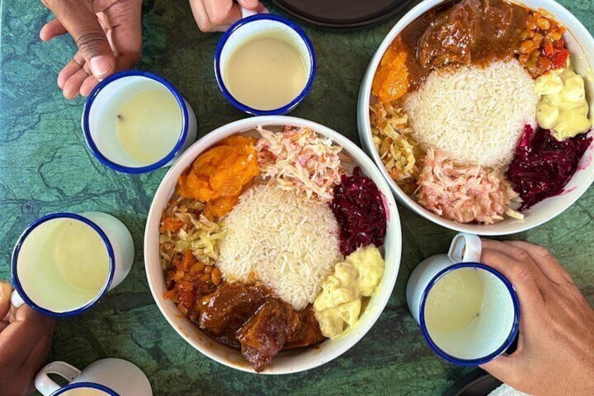 A meal with rice, vegetables, and meat, served in bowls and cups. 1