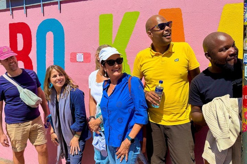 A group of people standing in front of a colorful wall with large letters. 4