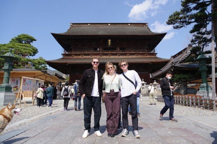 A traditional Japanese building with a tiled roof and wooden structure, surrounded by visitors and a dog. 4