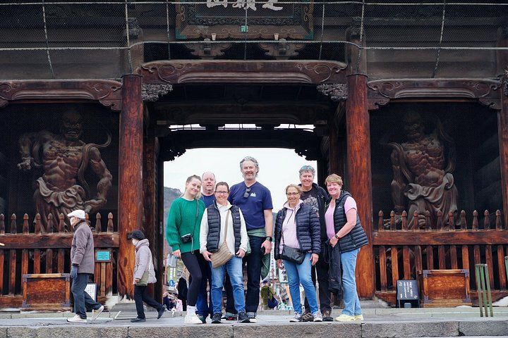 A group of people standing in front of a traditional wooden gate with intricate carvings. 2