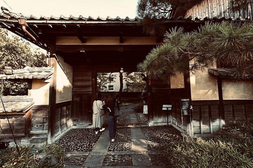 A traditional Japanese building with a tiled roof, a stone pathway, and a small garden area with plants. 2