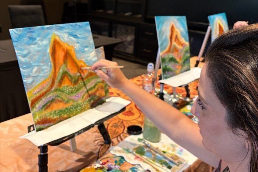 A person painting a landscape with mountains and water. 3