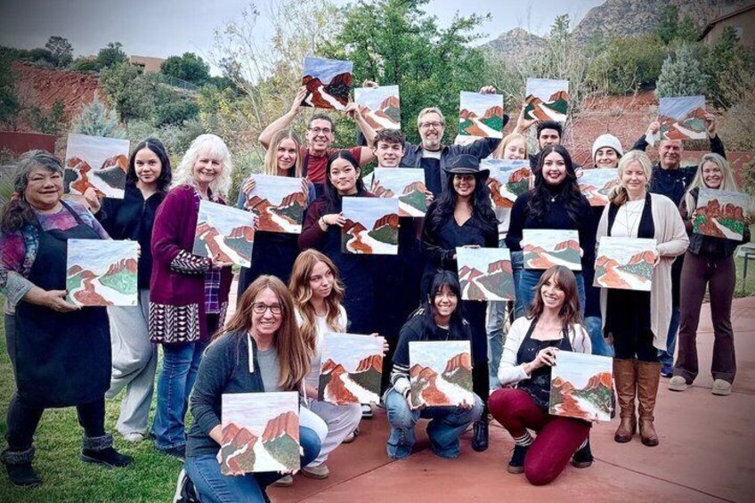 A group of people holding up paintings of a landscape. 5