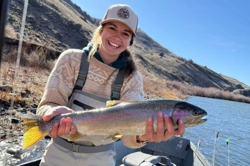 A person holding a large fish by a river. 4