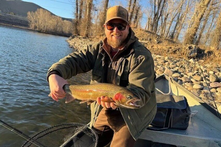 A person holding a fish by a river. 1