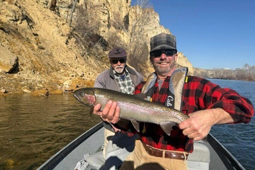Two people in a boat holding a fish. 5