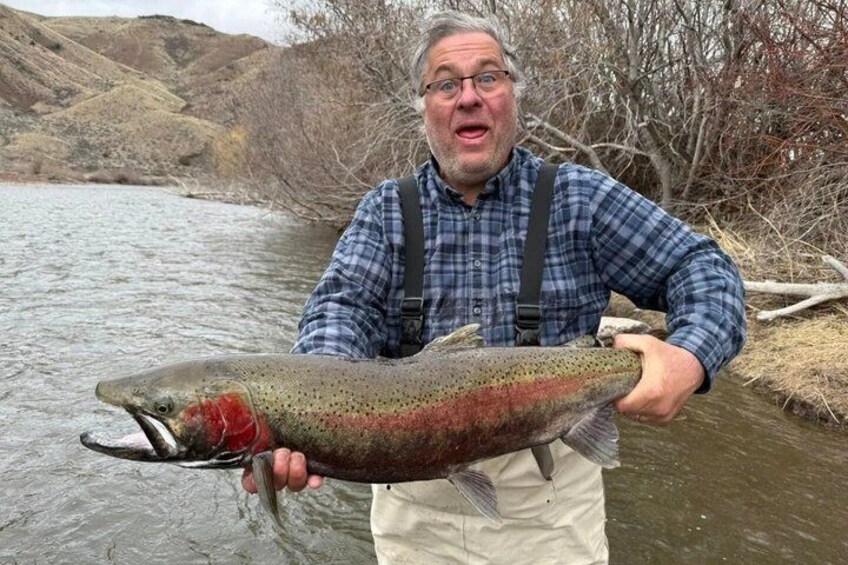 A person holding a large fish in a river. 3