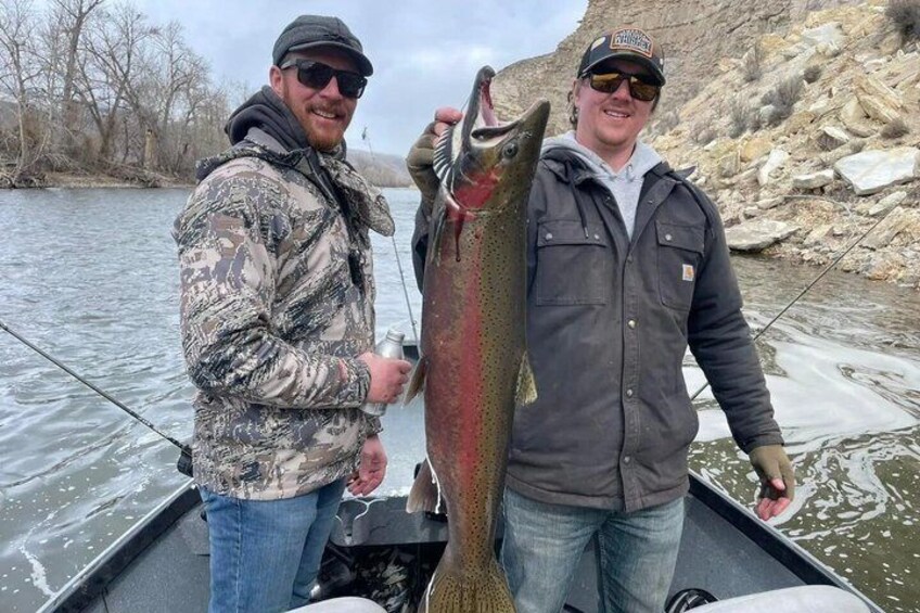Two people on a boat holding a large fish. 2