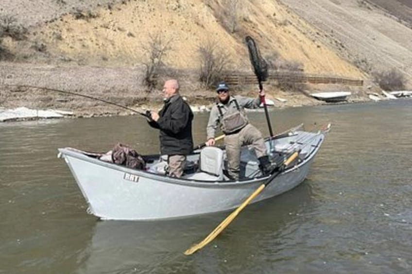 Two people fishing in a small boat on a river. 5
