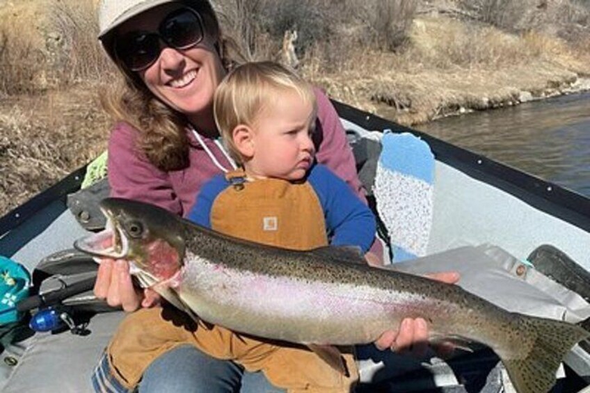A person holding a fish, wearing a hat, and a child sitting beside them. 2
