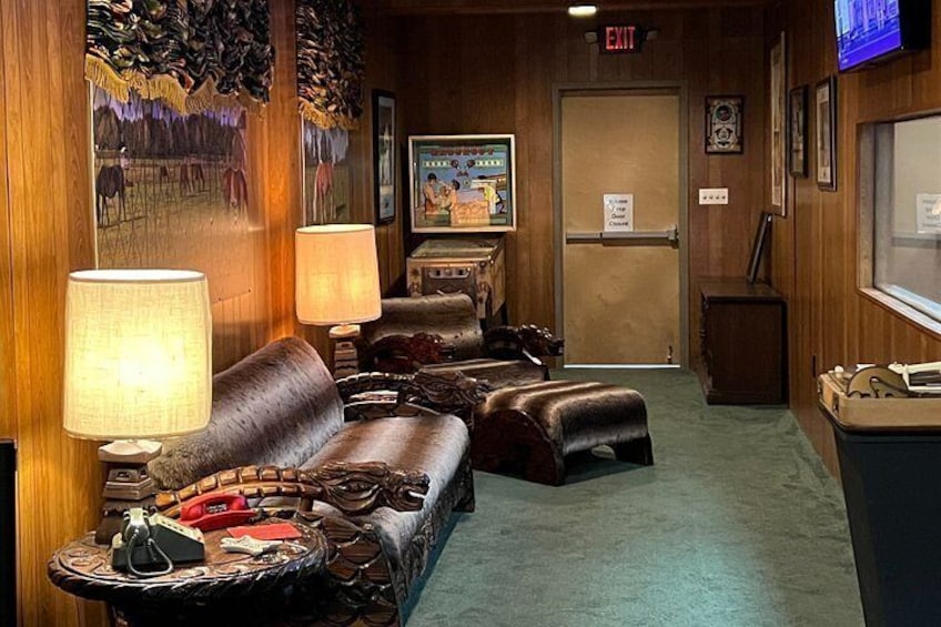 A cozy lobby with leather sofas, a wooden wall with a mural, a television, and a door marked 'EXIT'. 5