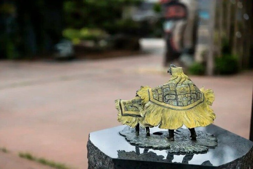 A small figurine of a person with a shield on a stone base outdoors. 5