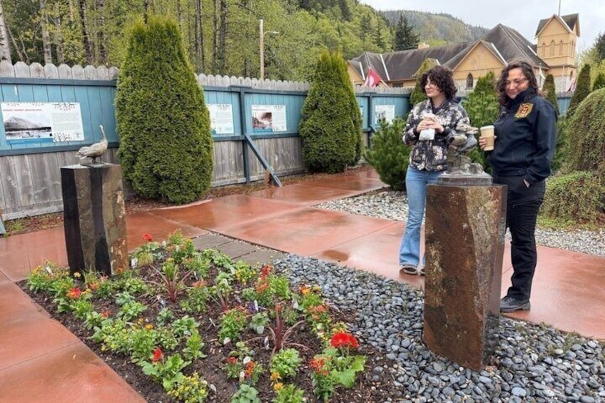 A garden with plants and two stone pillars, a wooden fence, and a building in the background. 4
