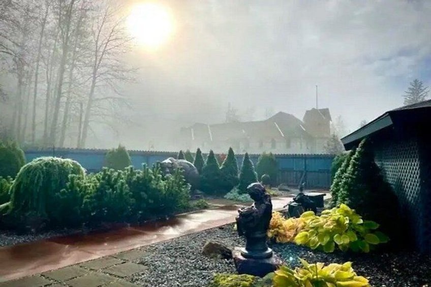 A foggy outdoor scene with a statue, greenery, and a building in the background. 3