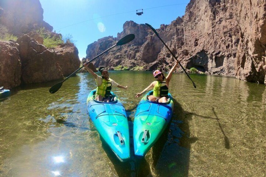 Two people kayaking in a canyon with clear water and rocky cliffs. 2