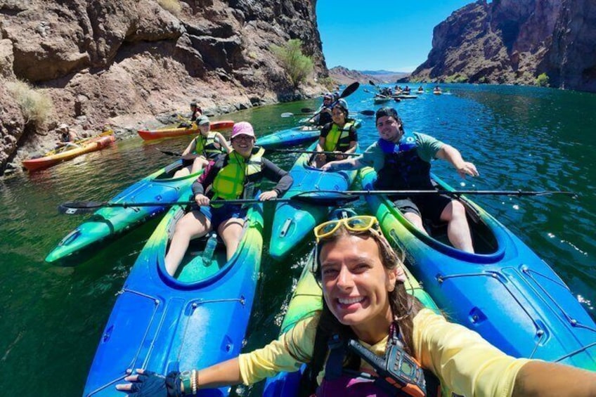 A group of people kayaking on a river surrounded by rocky cliffs. 3
