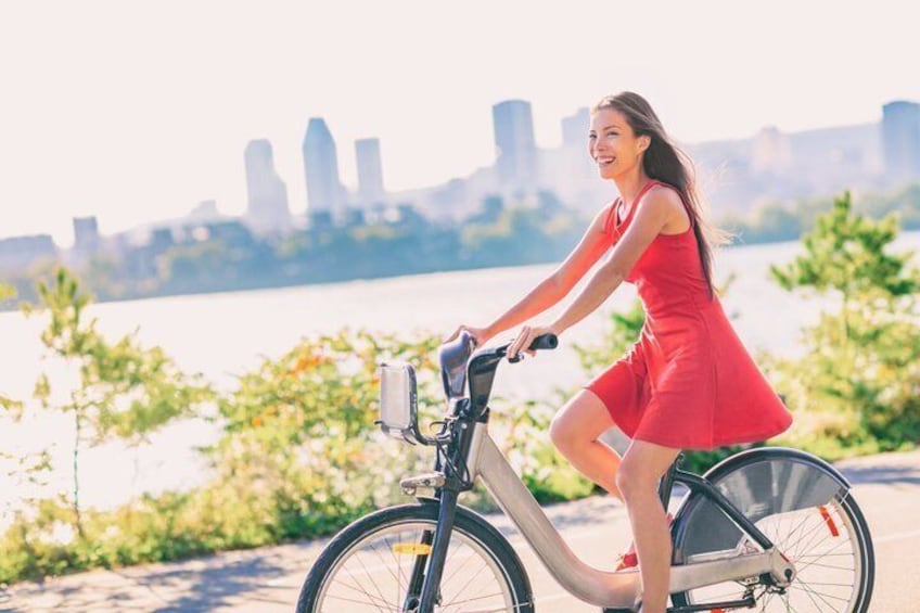 A person riding a bicycle with a city skyline in the background. 1