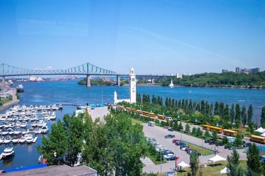 A marina with boats, a bridge, a clock tower, and a park with trees. 5