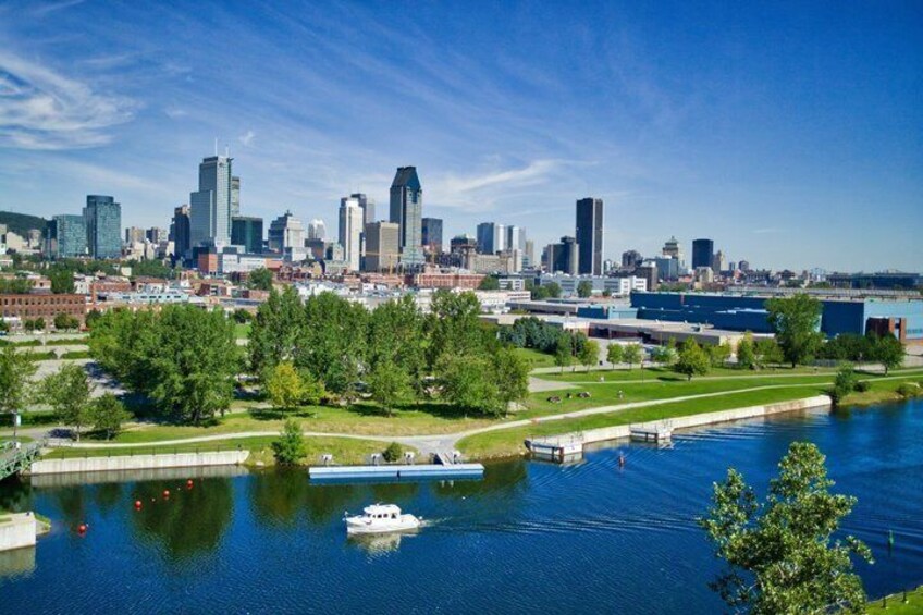 A city skyline with a river, boats, and green spaces. 4