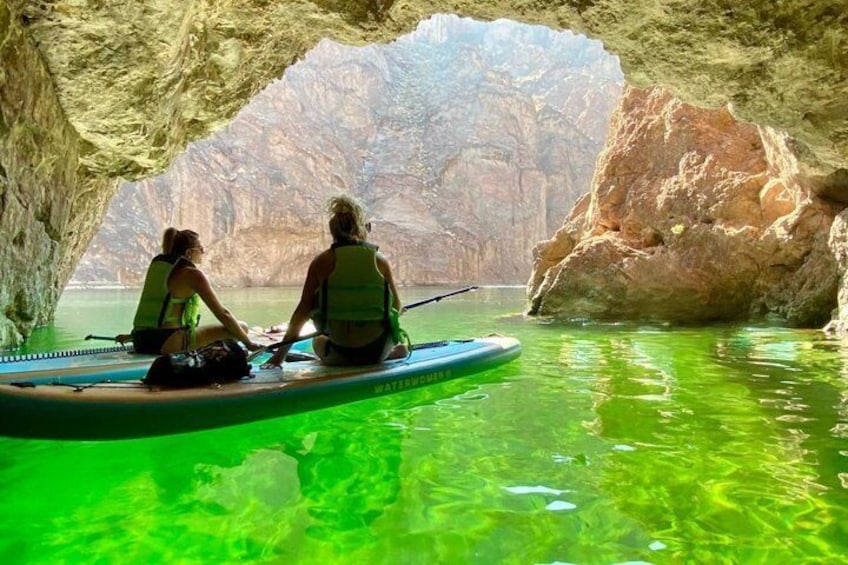 Two people kayaking in a cave with clear water. 1
