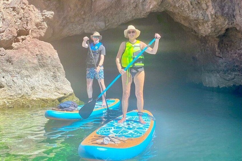 Two people paddleboarding in a cave-like water setting. 4
