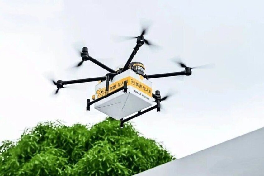 A drone with a yellow and black design flying against a clear sky. 2