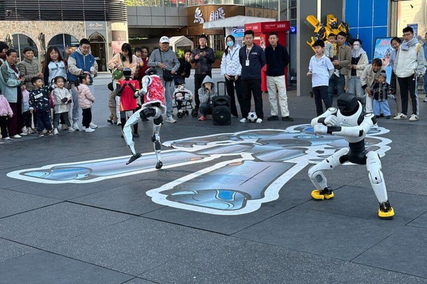 A street performer with a robotic figure, a crowd of onlookers, and a large, colorful pavement design. 3