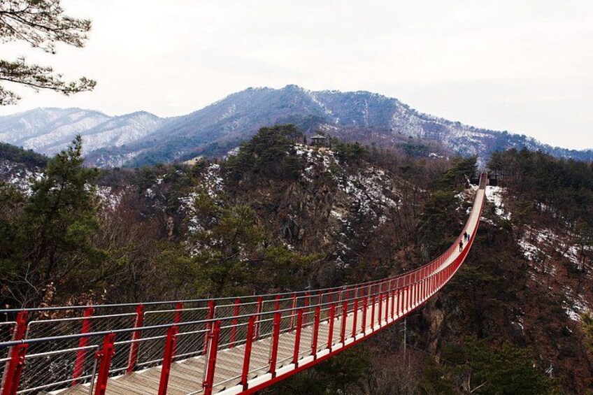 A red suspension bridge over a mountainous landscape. 3