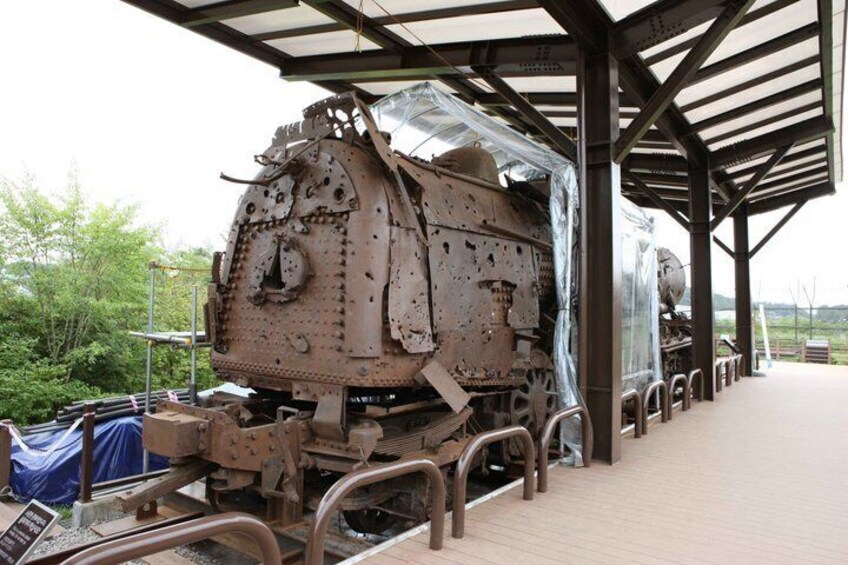 A large, rusted train engine under a covered structure with metal railings. 5
