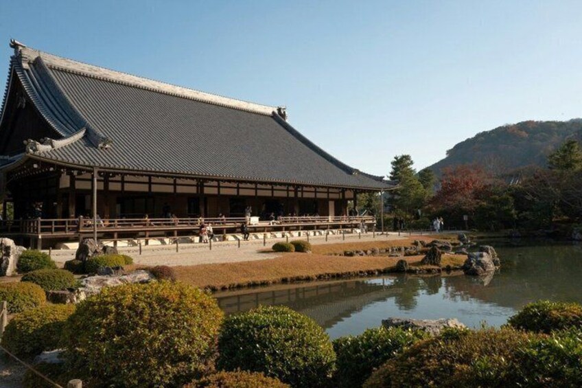 A traditional Japanese building with a tiled roof, surrounded by a pond and landscaped garden. 5