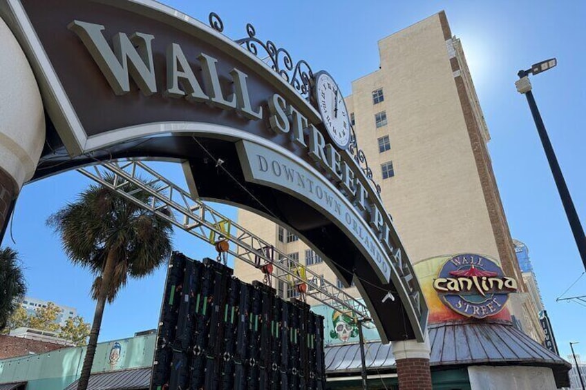 A large sign for 'Wall Street Downtown Orlando' with a 'Walt Disney World' logo and a 'Canine' sign. 3