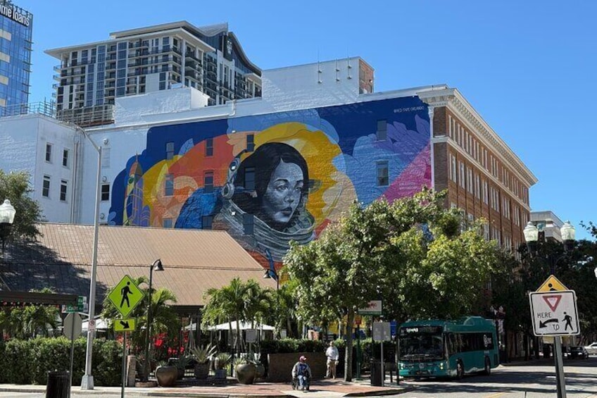 A mural on a building, a bus, and a pedestrian crossing sign. 2