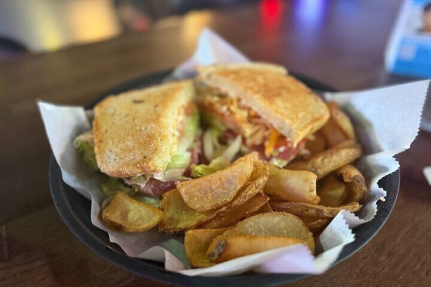 A grilled sandwich with fries in a paper-lined basket. 1