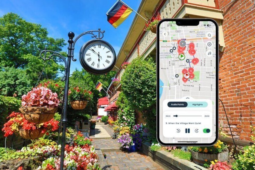 A street with a hanging clock, flower baskets, and a smartphone displaying a map with audio points. 1