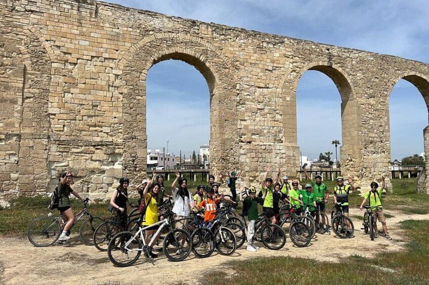 A group of cyclists in front of an ancient stone archway. 2