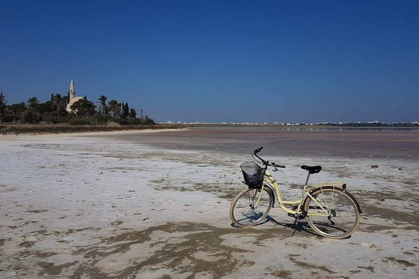 A beach with a bicycle and a church in the background. 2