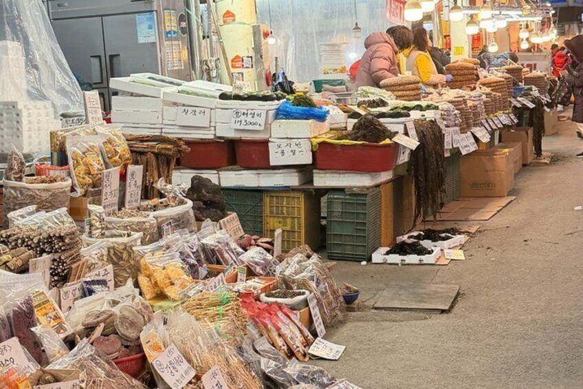 A bustling market with various food items and goods displayed on tables. 2