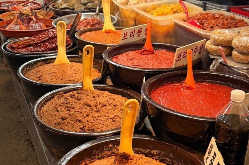 A variety of food items in large containers with labels, likely at a market. 3