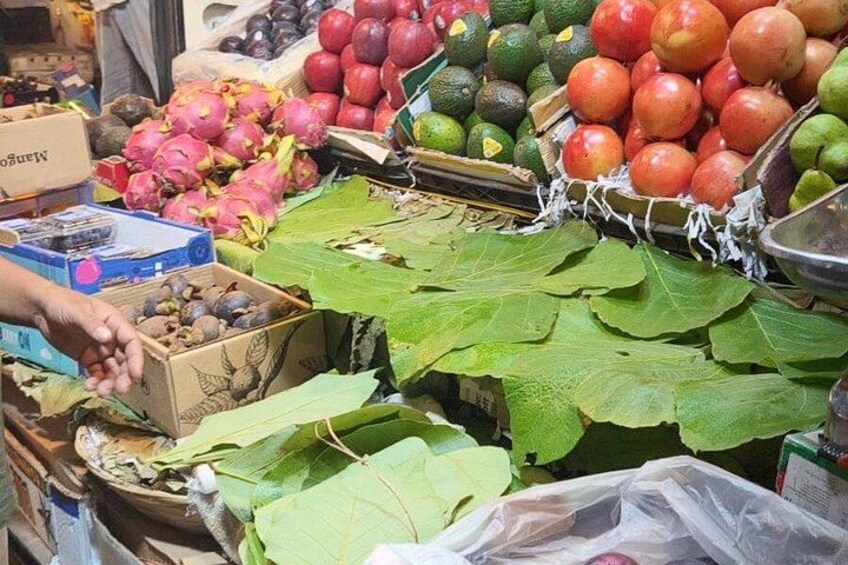 A market stall with various fruits and vegetables, including dragon fruit, apples, and avocados. 4