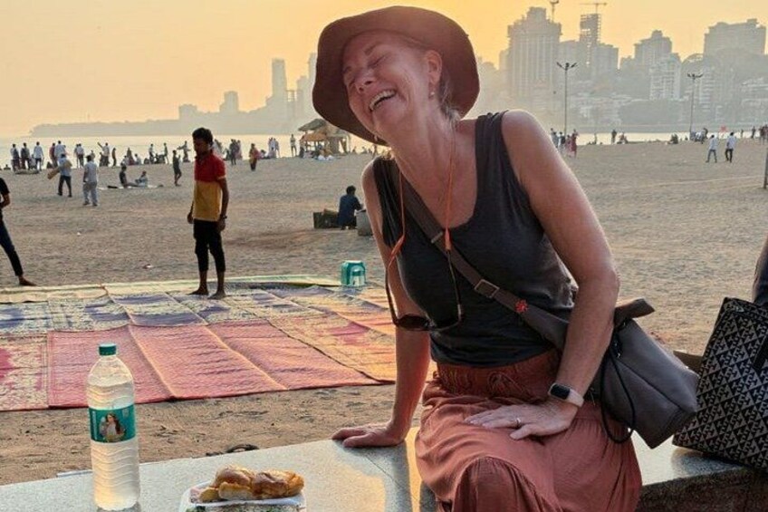 A person sitting on a bench at a beach with a city skyline in the background. 1