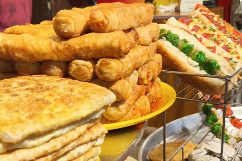 A variety of fried snacks including spring rolls, a pizza, and flatbreads. 3