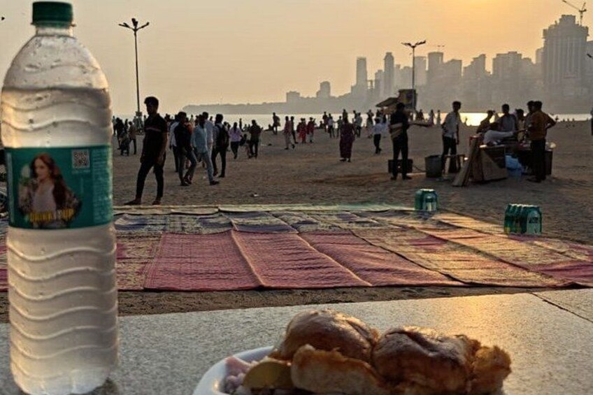 A beach with people, a bottle, and a plate of food. 5
