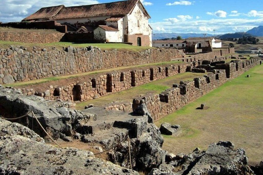 Ancient ruins with stone walls and a building with a tiled roof. 4