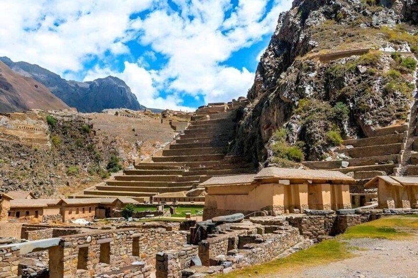 Ancient stone structures with terraced steps, a mountainous backdrop, and clear skies. 1