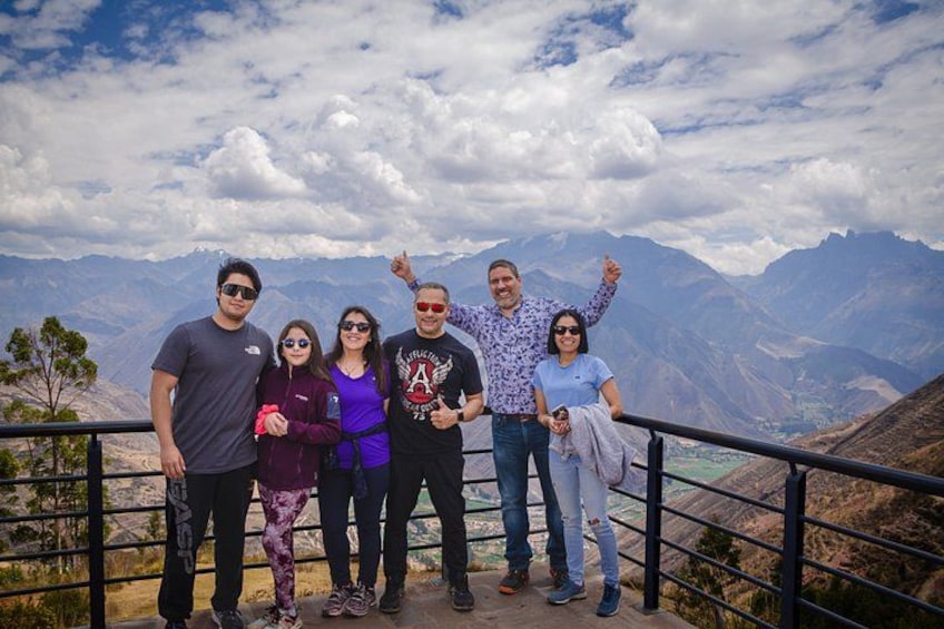 A group of people standing on a viewing platform with a mountainous landscape in the background. 2